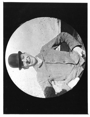 Outdoor portrait of young man in bowler and striped jacket.