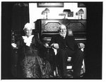 Portrait of seated elderly man and woman, in front of a piano.