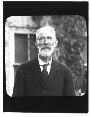 Portrait of an older bearded gentleman in front of an ivy covered building