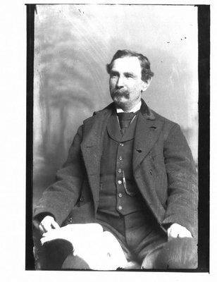 Portrait of an unidentified man, seated, with book on knee.