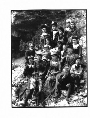 Portrait of a group, predominantly women and children, on a rocky river bank.