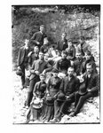 Group portrait of unidentified men and women on a rocky river bank.