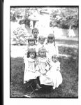 Outdoor portrait of a group of children, with a house in the background.