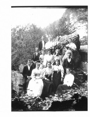 Group portrait of unidentified men and women on a rocky Elora river bank.