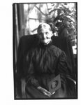 Portrait of an unidentified elderly woman, holding a child's portrait photograph.