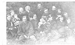 Outdoor group portrait of unidentified men, women and infants, seated on grass.