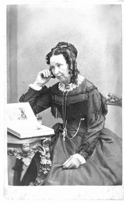 Portrait of an unidentified woman, seated, looking through a photograph album.