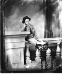 Studio portrait of an unidentified young boy sitting on a railing.