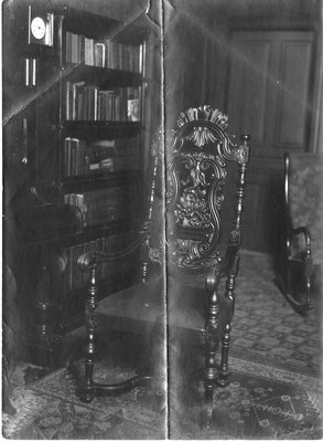 A room with bookshelves and an elaborately carved chair.