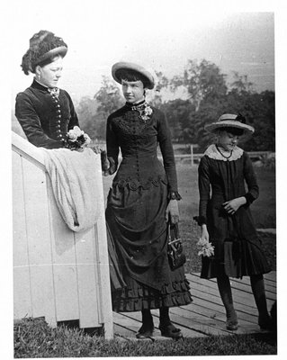 Outside portrait of a woman and two girls, standing on a boardwalk.