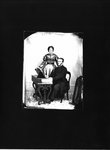 Portrait of a man, seated at a melodeon, and a woman, standing.