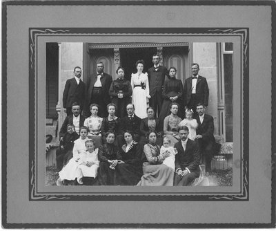 Group portrait of unidentified men, women and children, in a doorway.