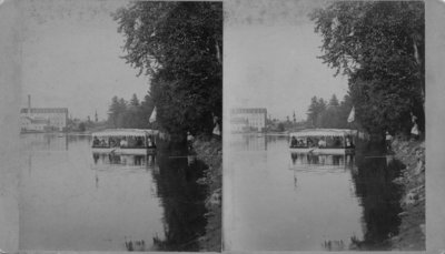 Pleasure boat on a body of calm water, with a factory in the background