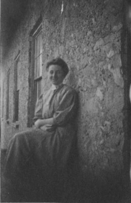 Portrait of a woman seated against a stone wall.