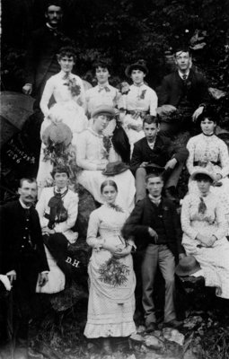 Group portrait of unidentified young men and women, on a rocky bank.