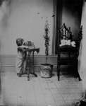John Connon, about 3 years of age, looking through a camera on a side table in his father’s studio