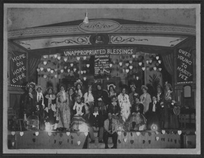 Cast of men and women in costume on stage of Armoury Hall, Elora