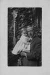 Portrait of John Connon holding a small child in a light coloured dress.