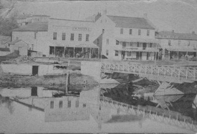 Looking across the river to buildings on Mill St., Elora, with the bridge in the foreground.