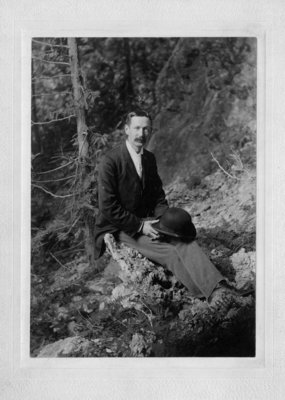 John Connon, sitting on a tree stump.