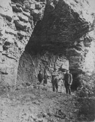 Two men and two boys standing against the rock of the Elora Gorge