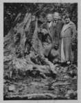 Portrait of John Connon with an unidentified man and woman, standing beside a tree stump.