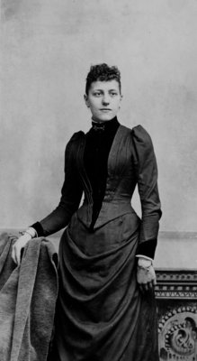 Portrait of an unidentified young woman in a fitted dark dress.