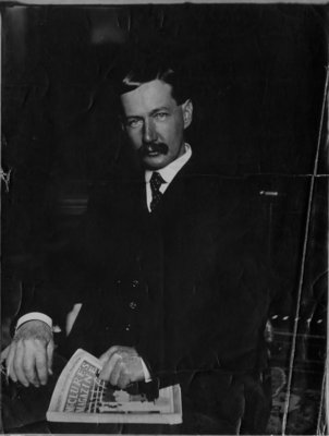 Portrait of John Connon, seated, holding a copy of McClure's Magazine.