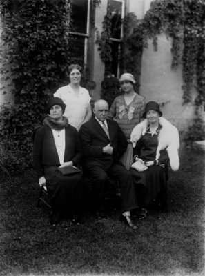 Group portrait of 5 unidentified people [4 women, 1 man] in front of a vine covered building.