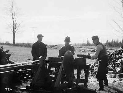 Three Unidentified Men Sawing Wood With a Circular Saw