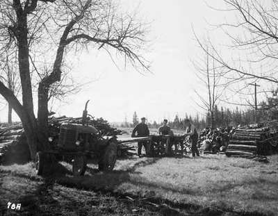 Three Unidentified Men Sawing Wood With a Circular Saw