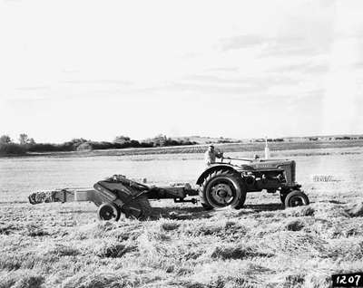 Unidentified Man Pulling a Hay Baler with a Tractor