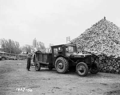 Tractor With a Homemade Cab Next to Lumber Pile