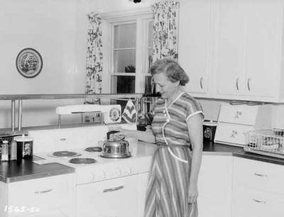 Unidentified Woman Standing Next to a Kitchen Stove