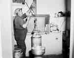 Man Using a Pulley to Lift Milk Can into Cooler