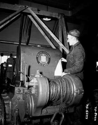 Man Standing Next Behind a Tractor Mounted Winch