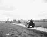 Unidentified Man Riding a Tractor Down a Dirt Road