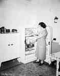 Unidentified Woman Standing in Kitchen with Fridge Door Open, Englehart, ON