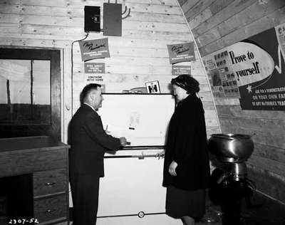 Salesman Shows a Female Customer a Freezer