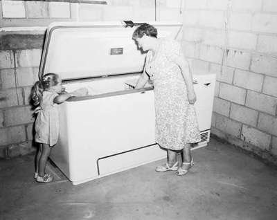 Unidentified Woman and Child Look into Freezer